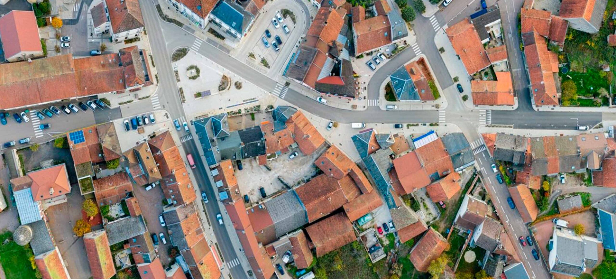 Vue aérienne d'un centre-bourg avec place réaménagée et espaces plantés au carrefour des rues principales.