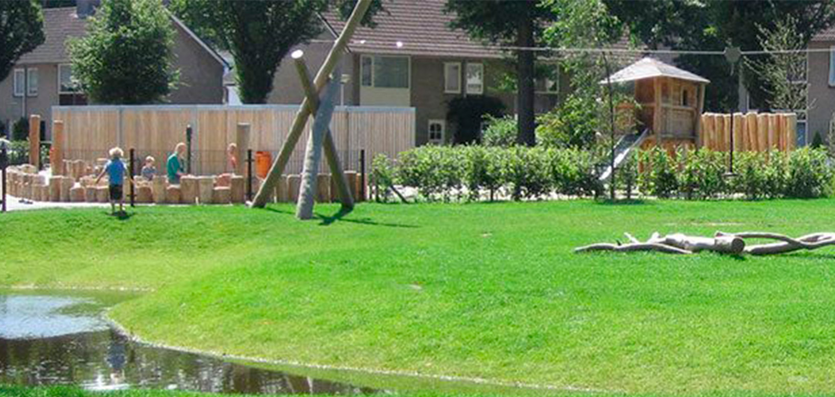 Aire de jeux paysagère avec pelouse, bassin et structures en bois dans un espace vert résidentiel.