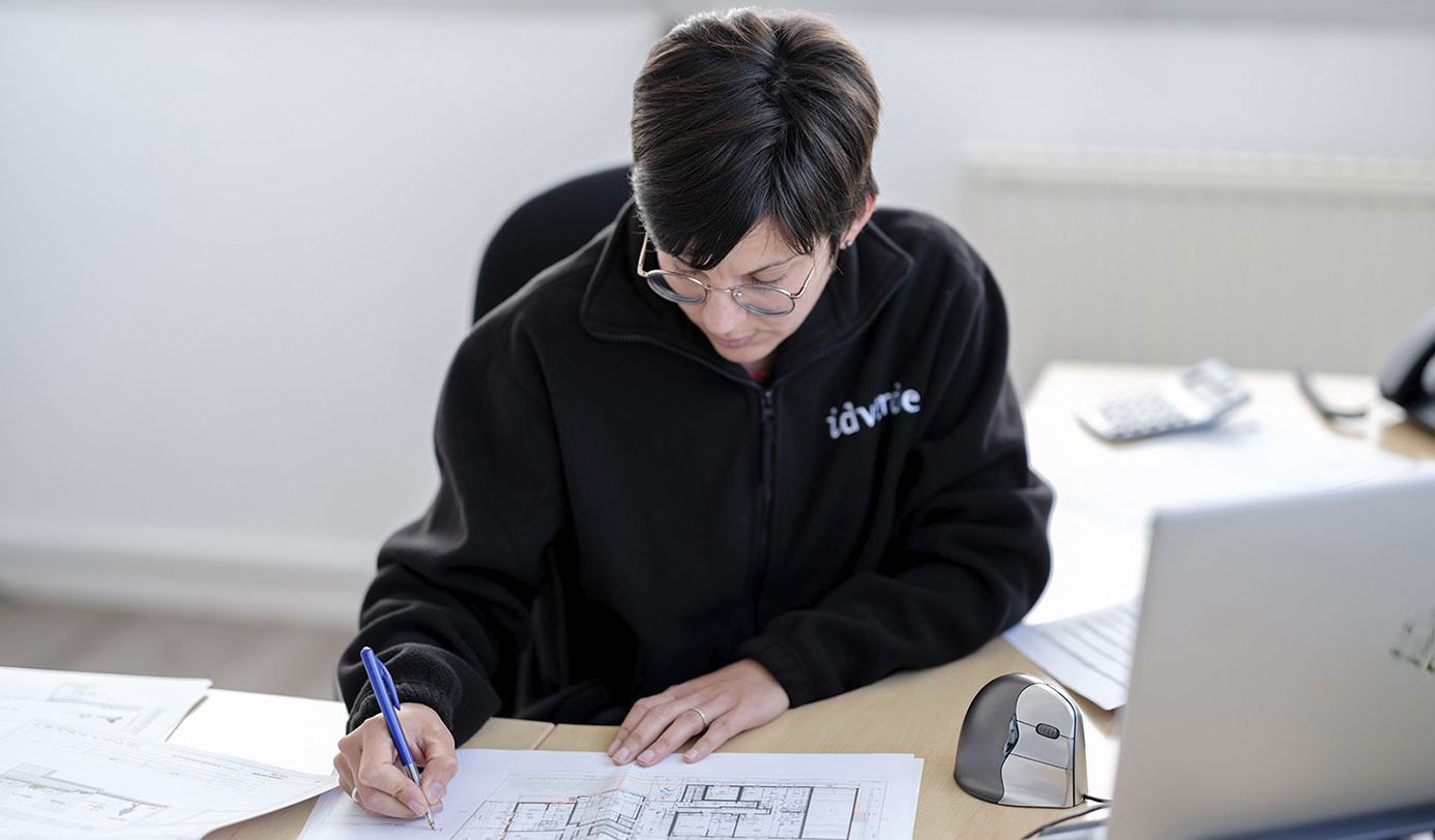Une collaboratrice idverde étudie un plan technique à son bureau.