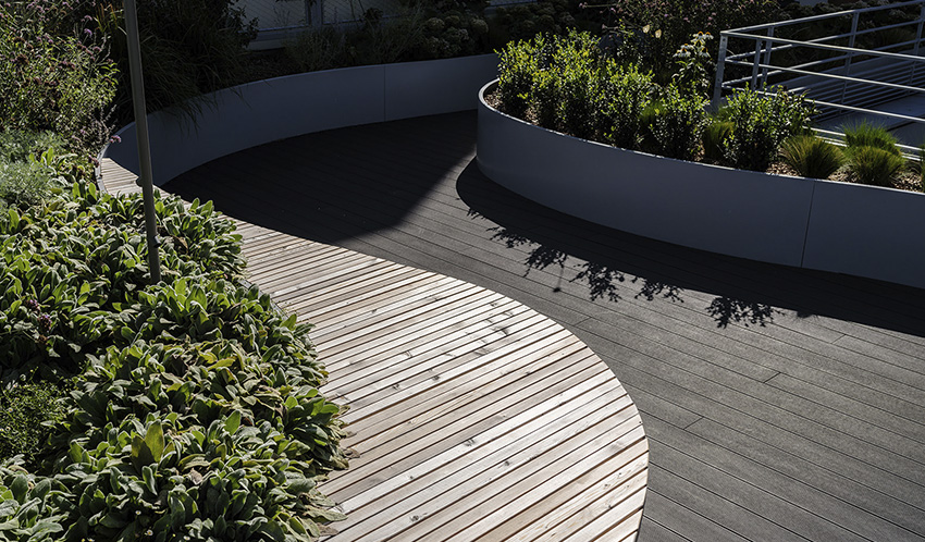 Toiture-terrasse végétalisée avec caillebotis bois et bacs de plantation arrondis.