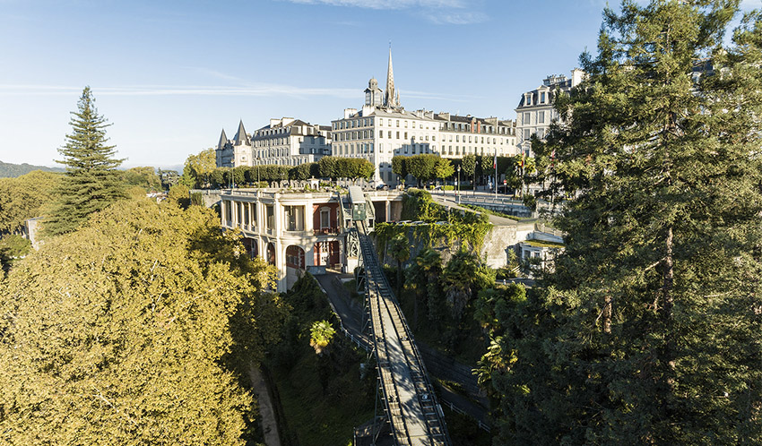 Vue aérienne d'un funiculaire entouré d'arbres et d'espaces verts en centre-ville.