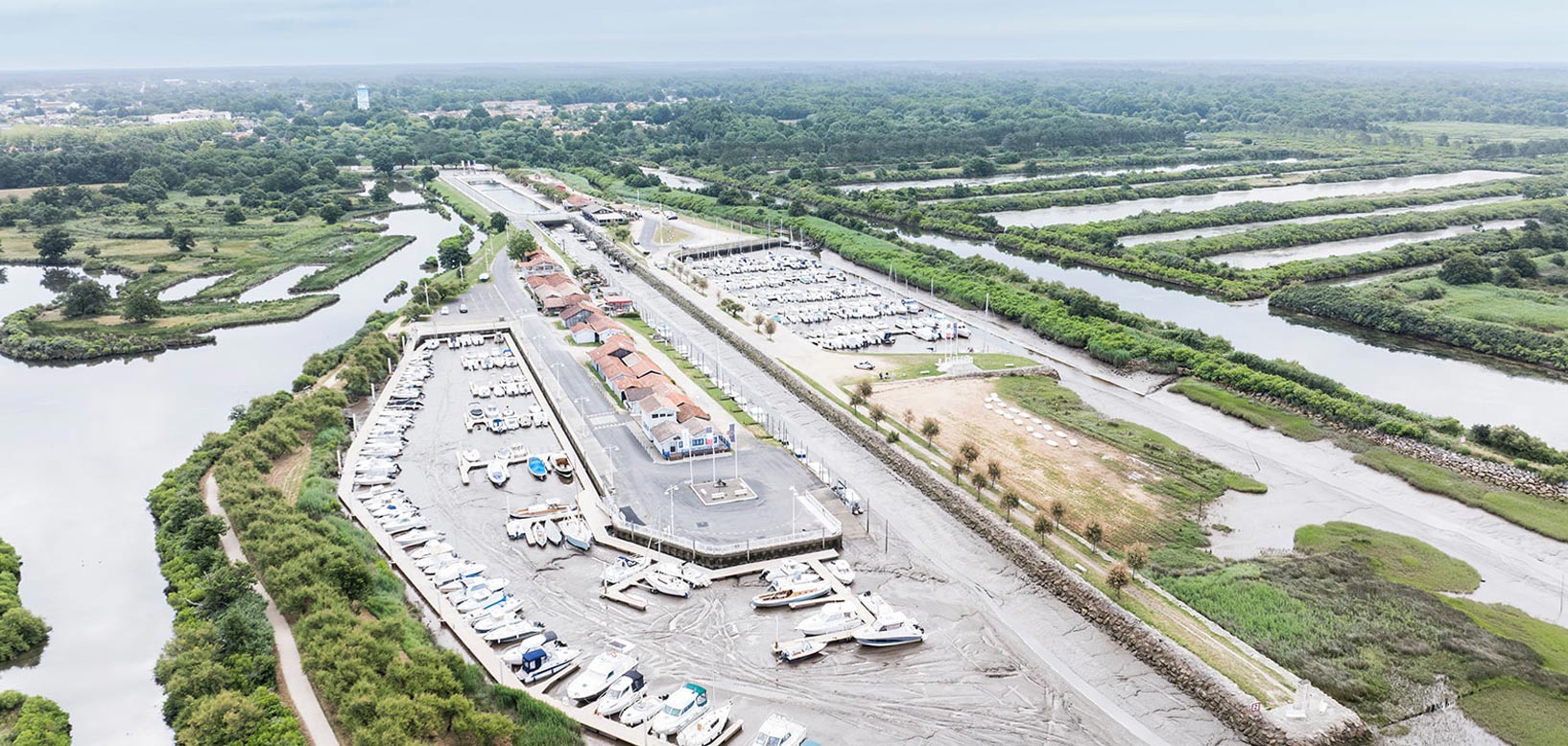 Vue aérienne d'un port de plaisance entouré de marais et de canaux paysagers.
