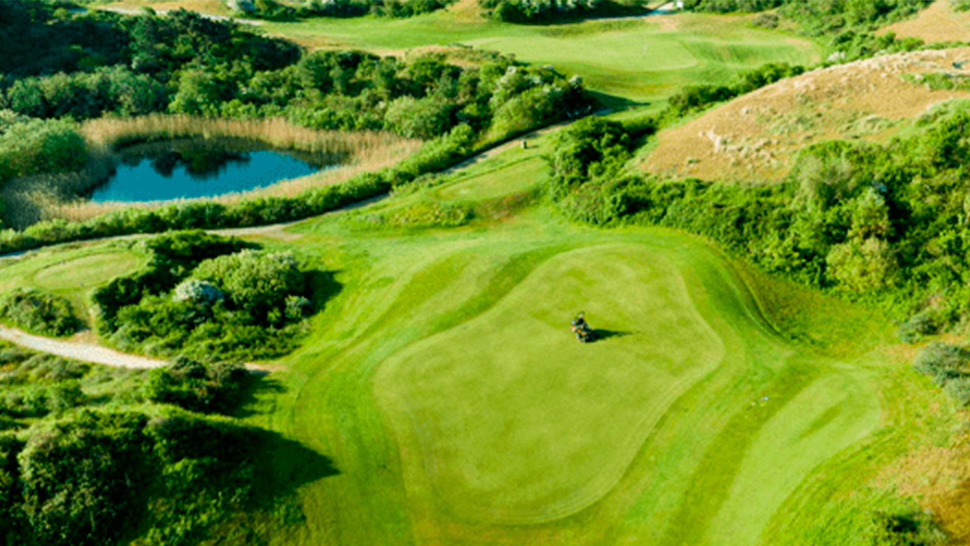 Vue aérienne d'un parcours de golf verdoyant avec étang et végétation naturelle préservée