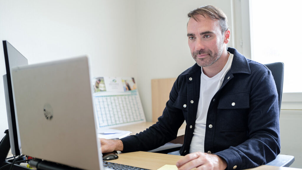 Un responsable de projet paysager travaille sur son ordinateur portable dans un bureau professionnel