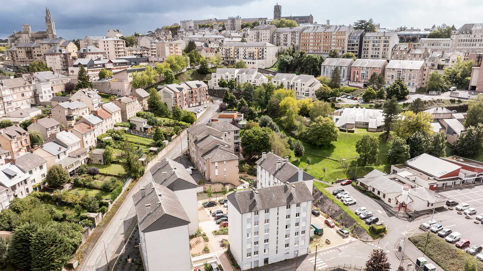 Vue aérienne d'une ville française avec espaces verts urbains, immeubles résidentiels et cathédrale en arrière-plan