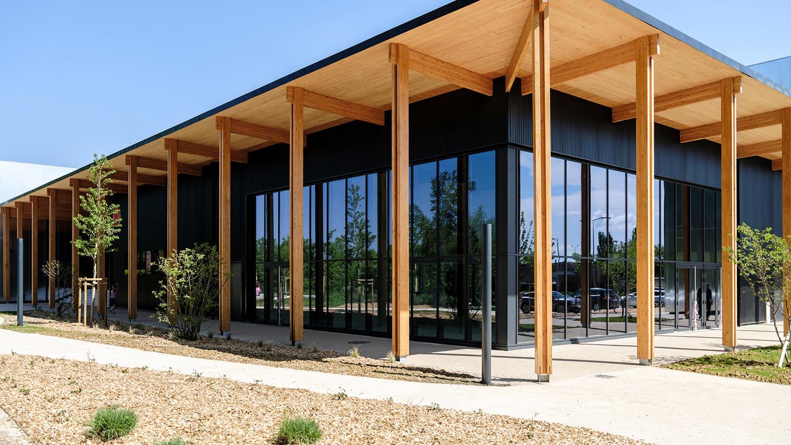 Façade moderne de l'IUT de Toulon avec structure en bois et grandes baies vitrées entourée de végétation