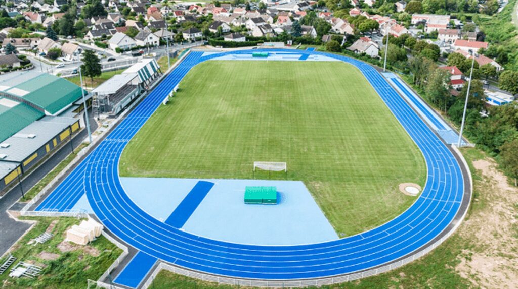 Vue aérienne d'un stade d'athlétisme à piste bleue au cœur d'une ville