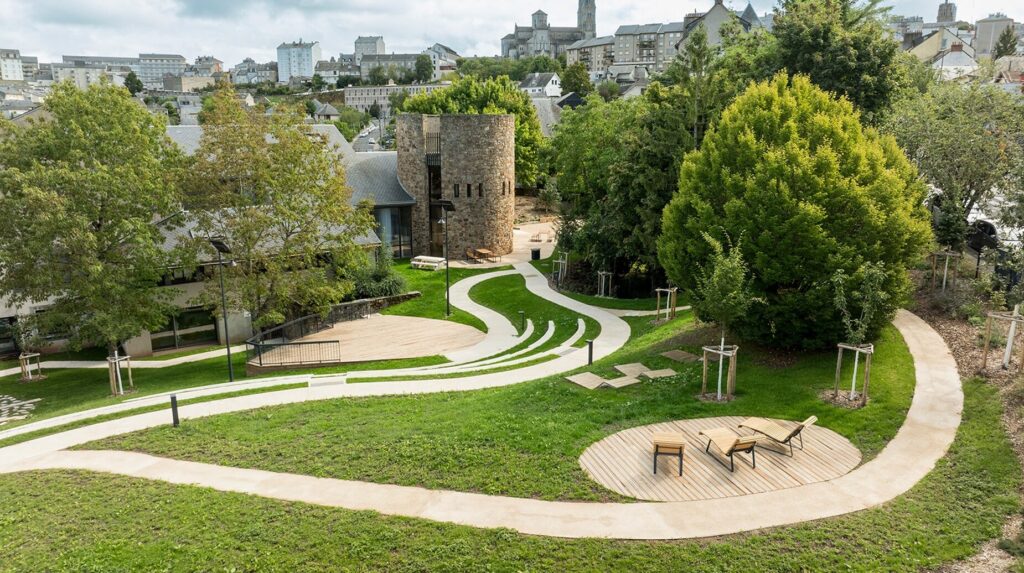 Parc urbain en gradins engazonnés surplombé par une ville en pente