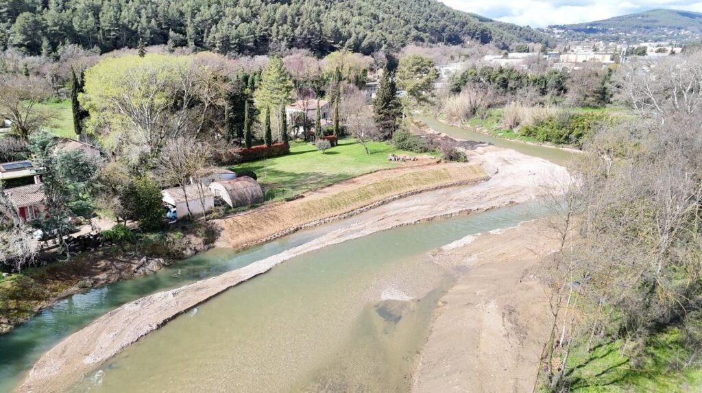 Rivière traversant une vallée boisée bordée de jardins et d'habitations