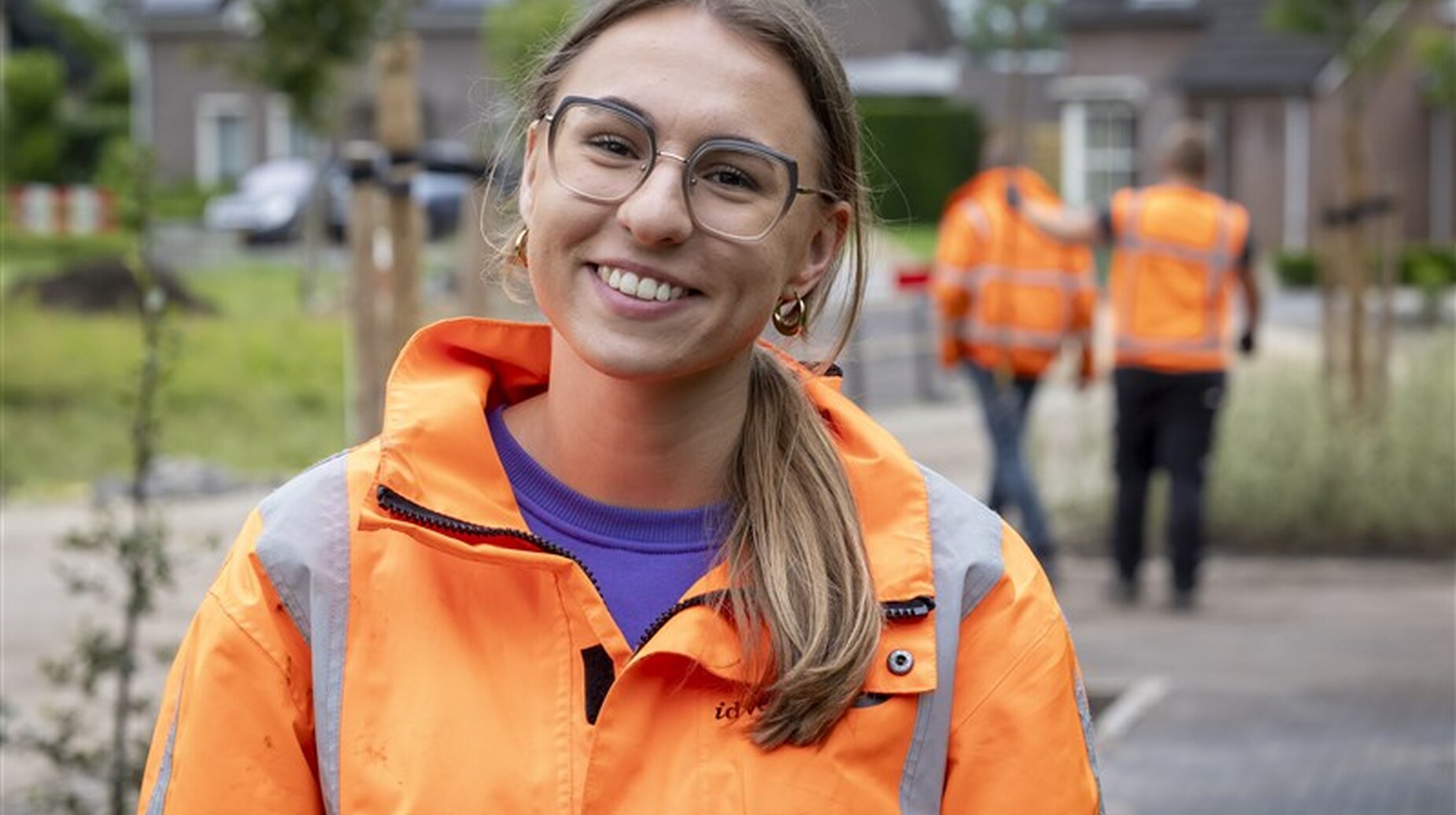 Portrait souriant d'une paysagiste en veste orange sur un chantier résidentiel