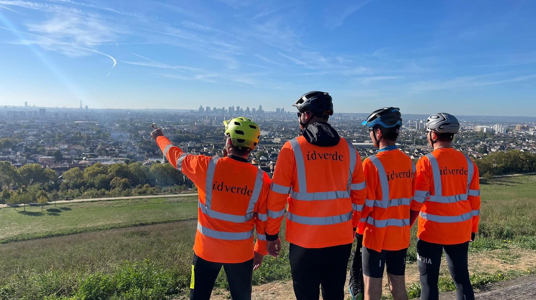 Groupe de collaborateurs idverde en tenue haute visibilité surplombant un panorama urbain