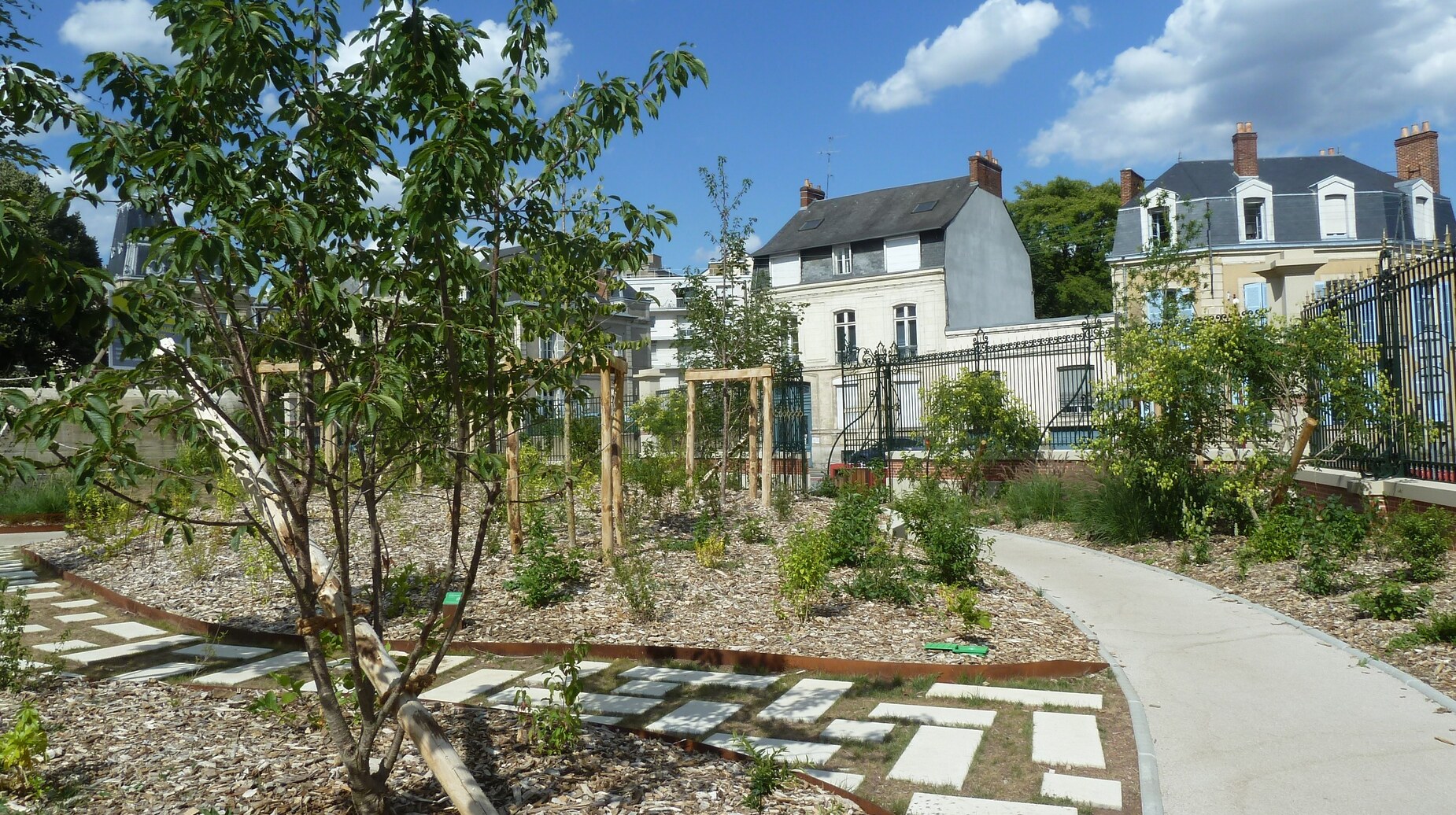Jardin nouvellement planté avec cheminement en pas japonais devant des demeures anciennes