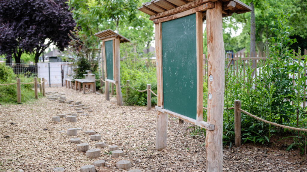 Jardin pédagogique avec panneaux d'affichage en bois et cheminement en pas de bois