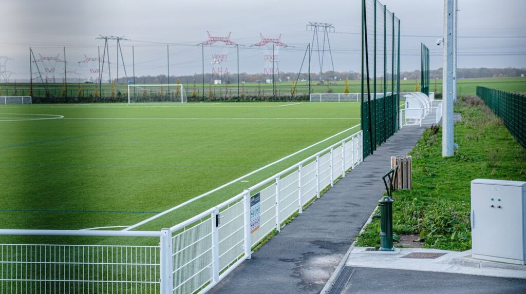 Terrain de football en gazon entouré de clôtures et de pare-ballons