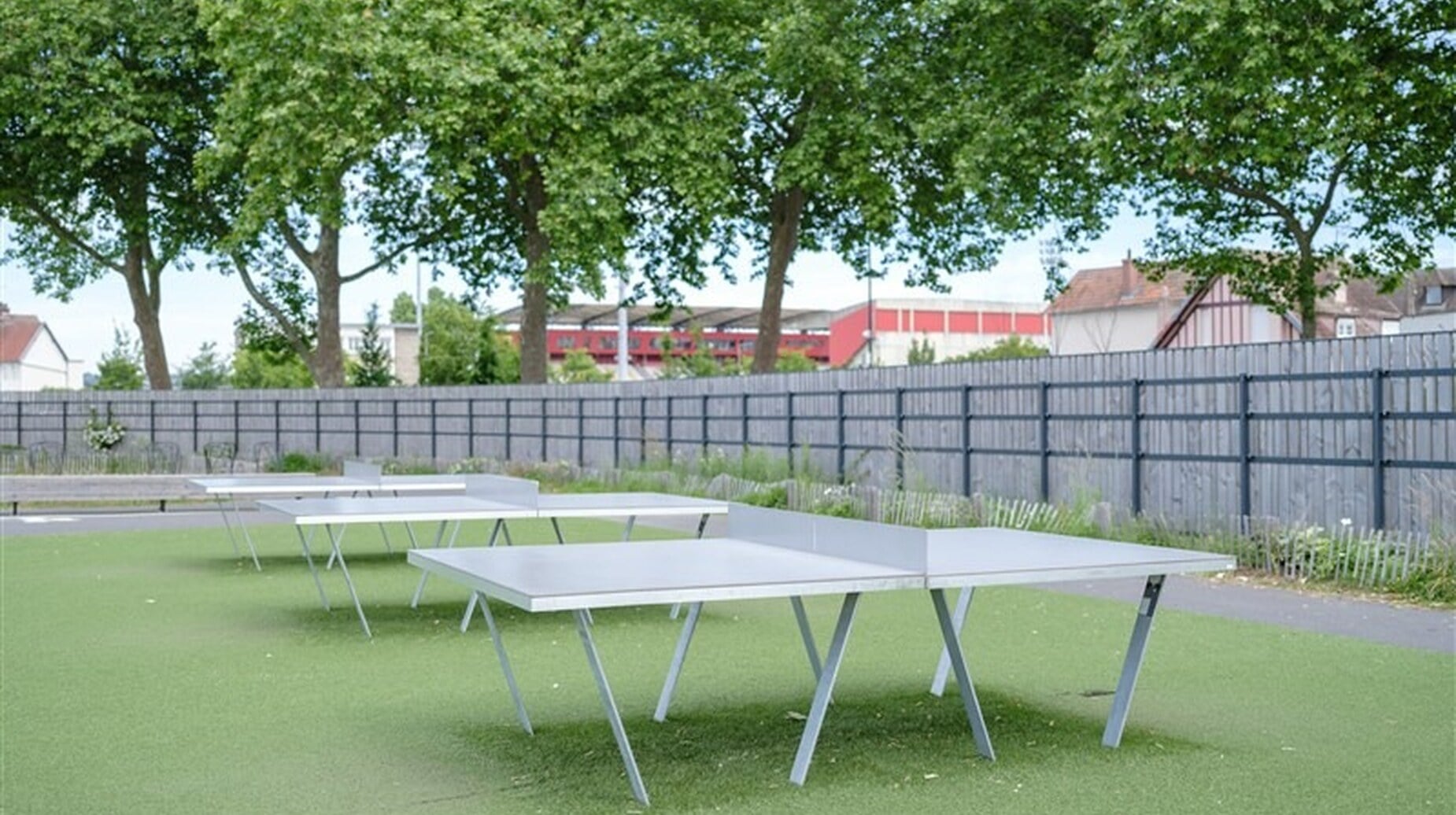Tables de tennis de table en extérieur sur sol souple à l'ombre des arbres