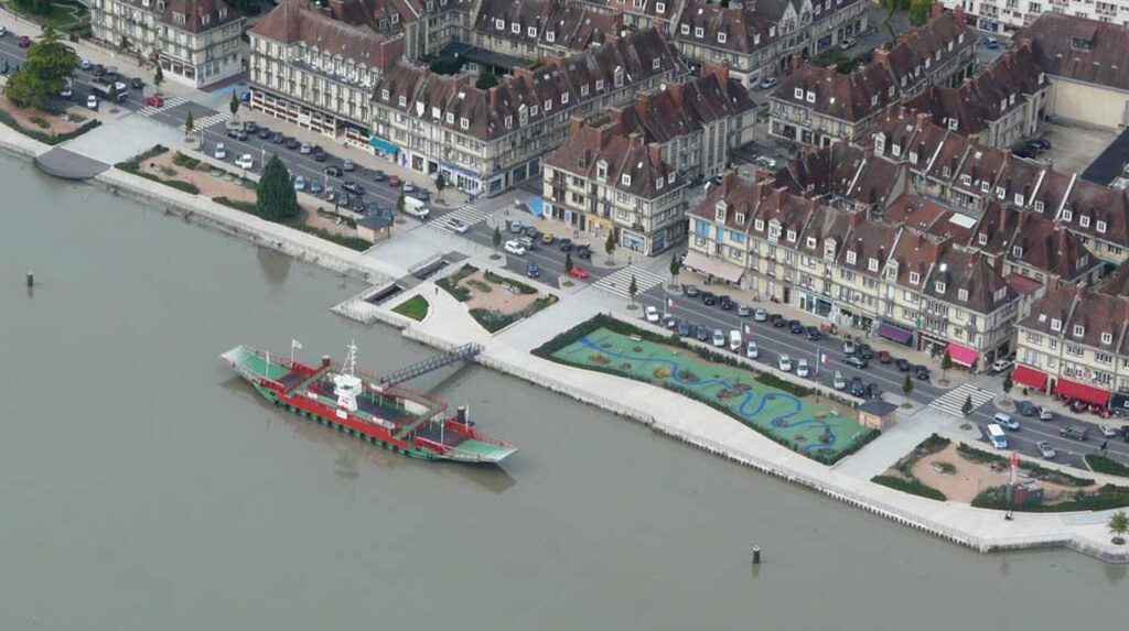 Vue aérienne d'un front de mer avec promenade paysagée, bassin et bateau amarré