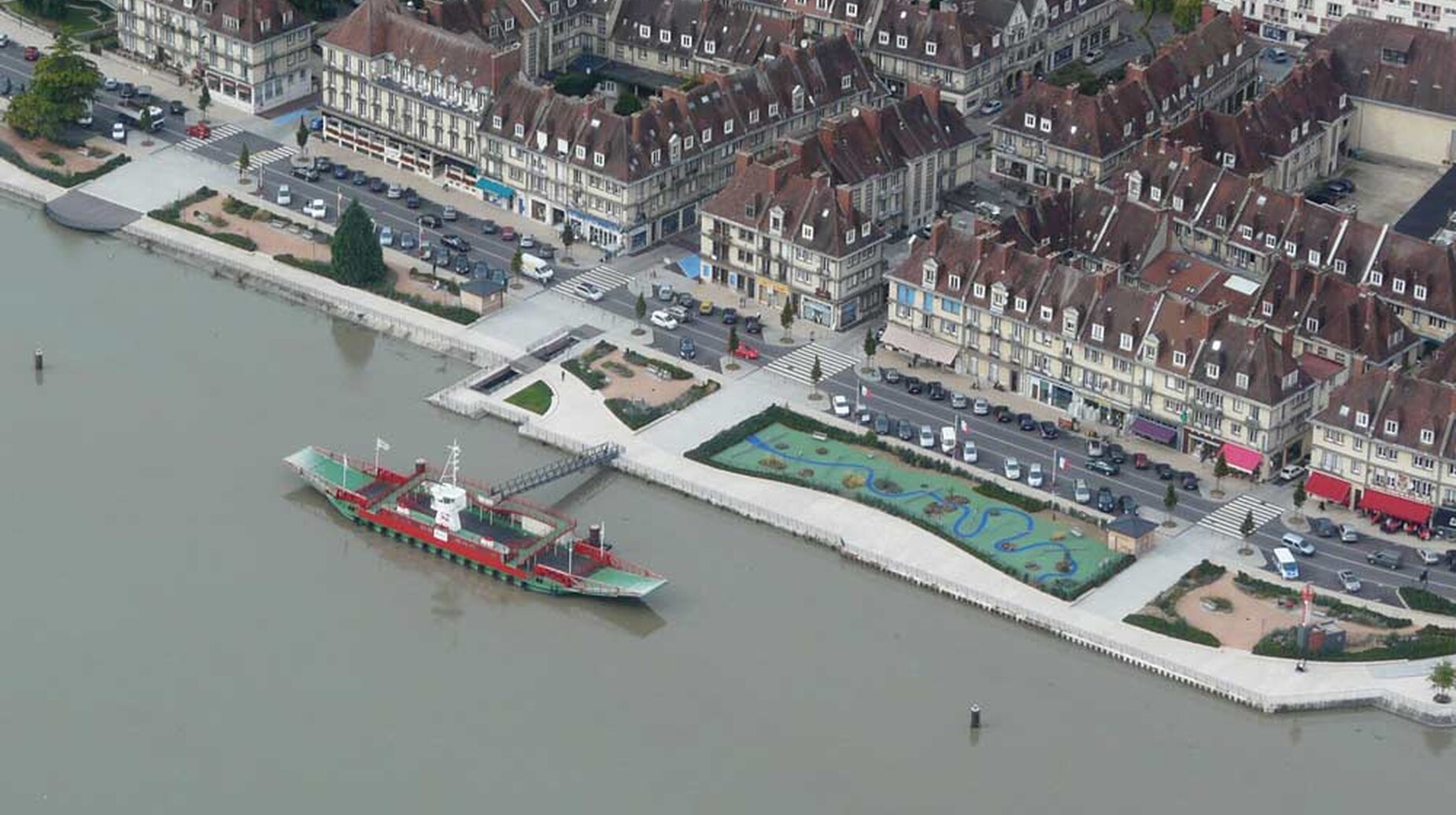 Vue aérienne d'un front de mer avec promenade paysagée, bassin et bateau amarré