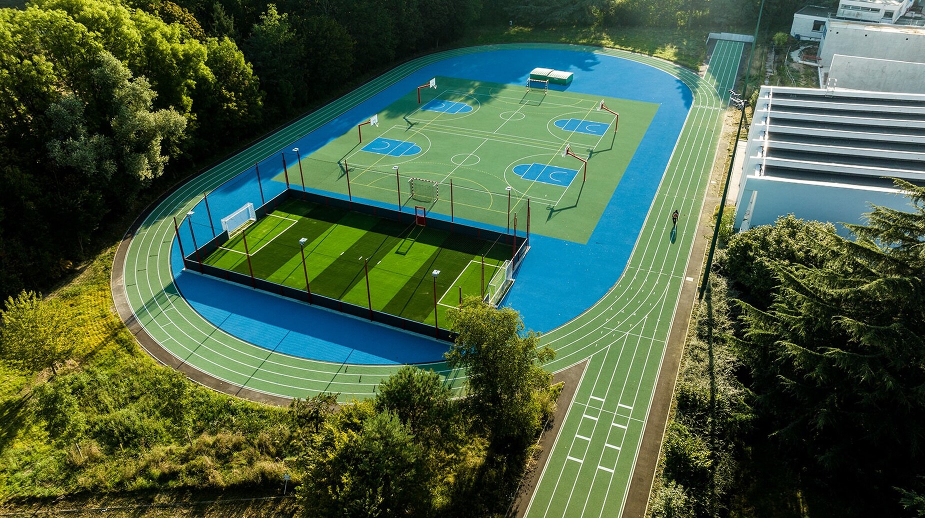 Vue aérienne d'un complexe sportif avec piste d'athlétisme entouré de boisements