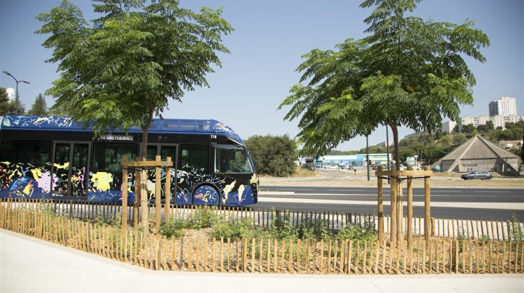 Station de tramway bordée de jeunes arbres et de ganivelles en milieu urbain