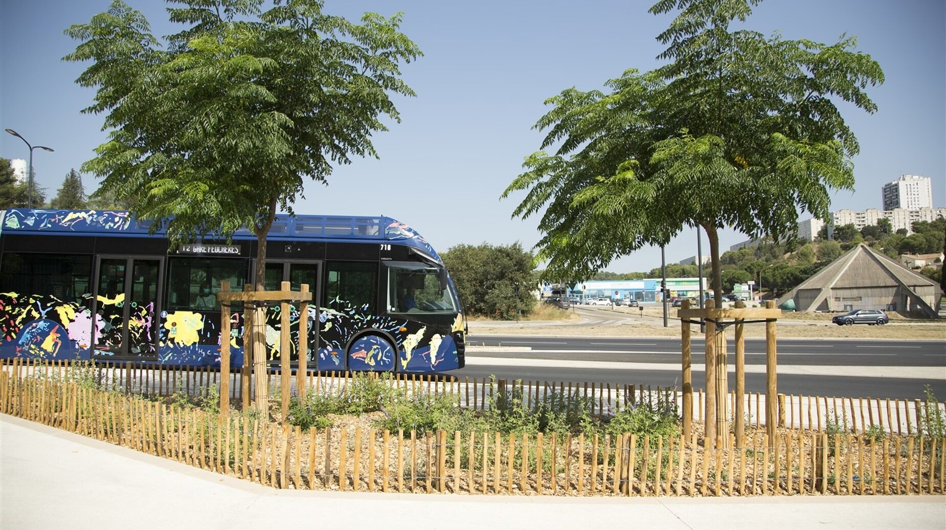 Station de tramway bordée de jeunes arbres et de ganivelles en milieu urbain