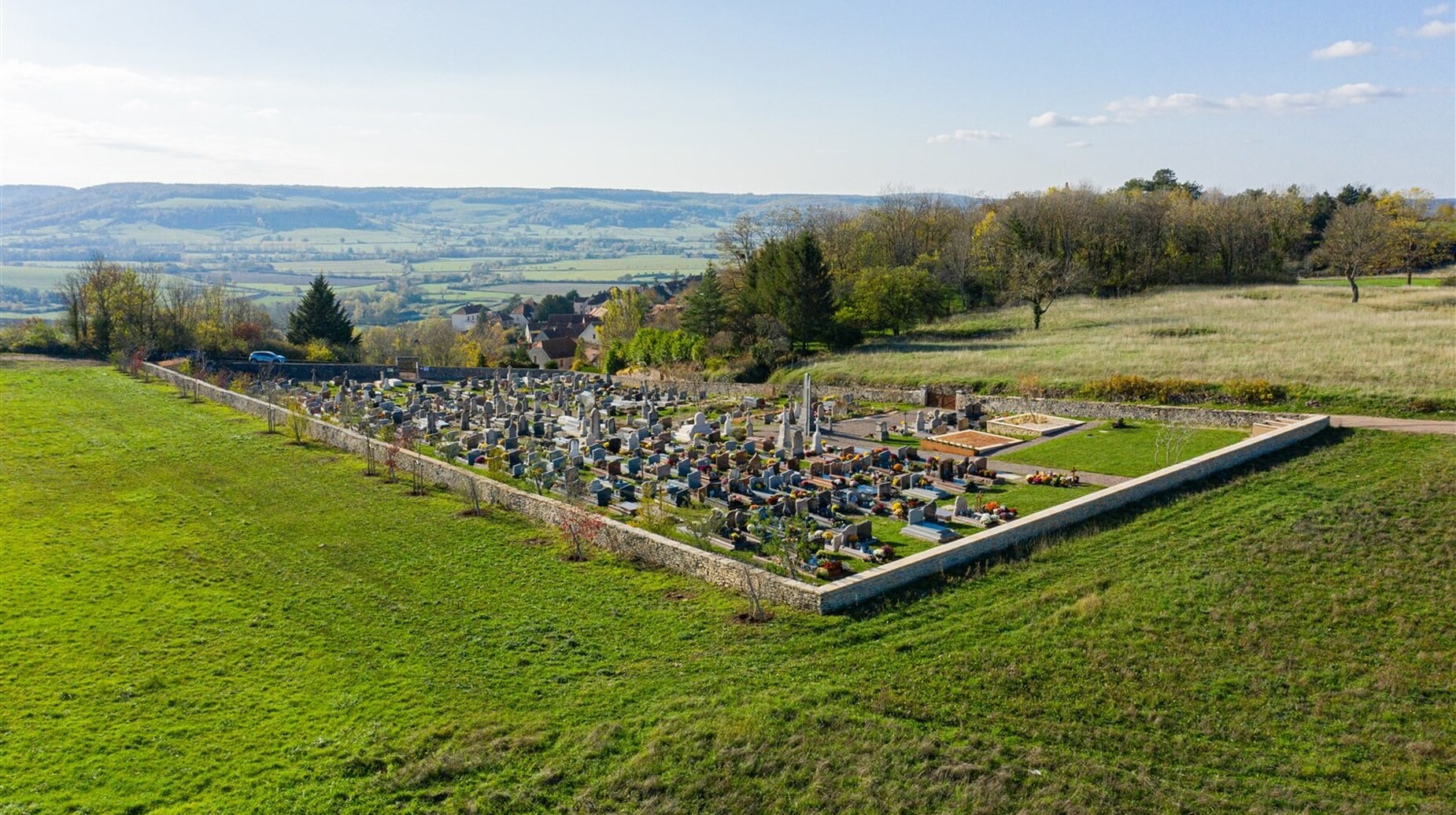 Vue aérienne d'un cimetière entouré de prairies et de collines