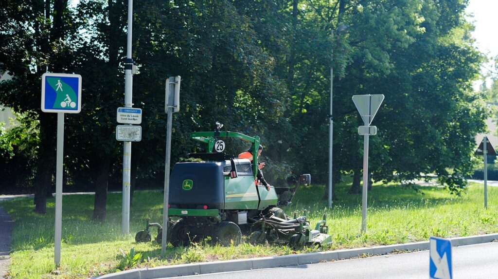 Tondeuse professionnelle intervenant sur un accotement routier arboré