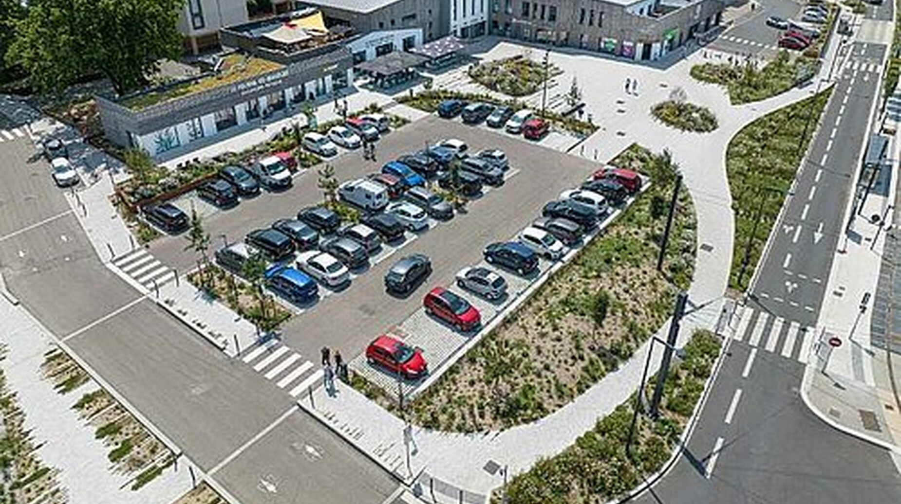 Vue aérienne d'un parking paysager avec noues plantées et cheminements piétons