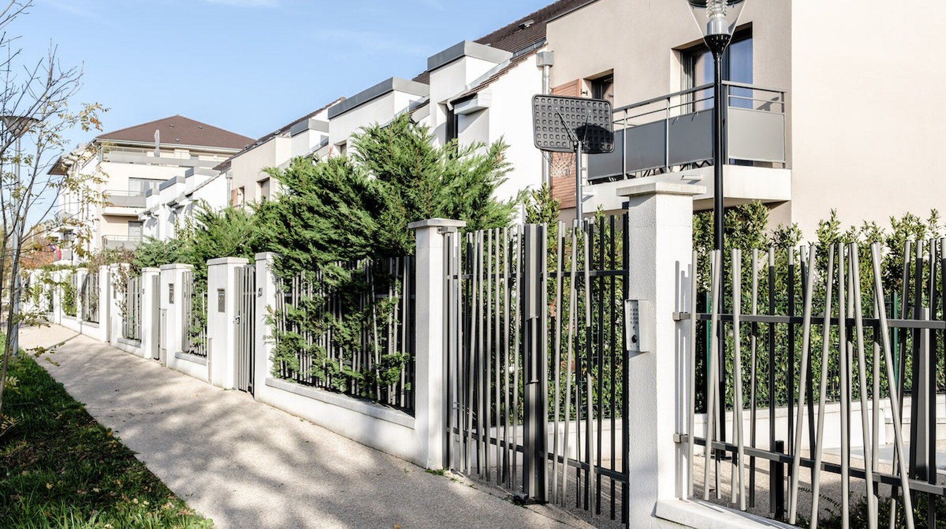 Rue résidentielle bordée de clôtures et de haies devant des maisons contemporaines